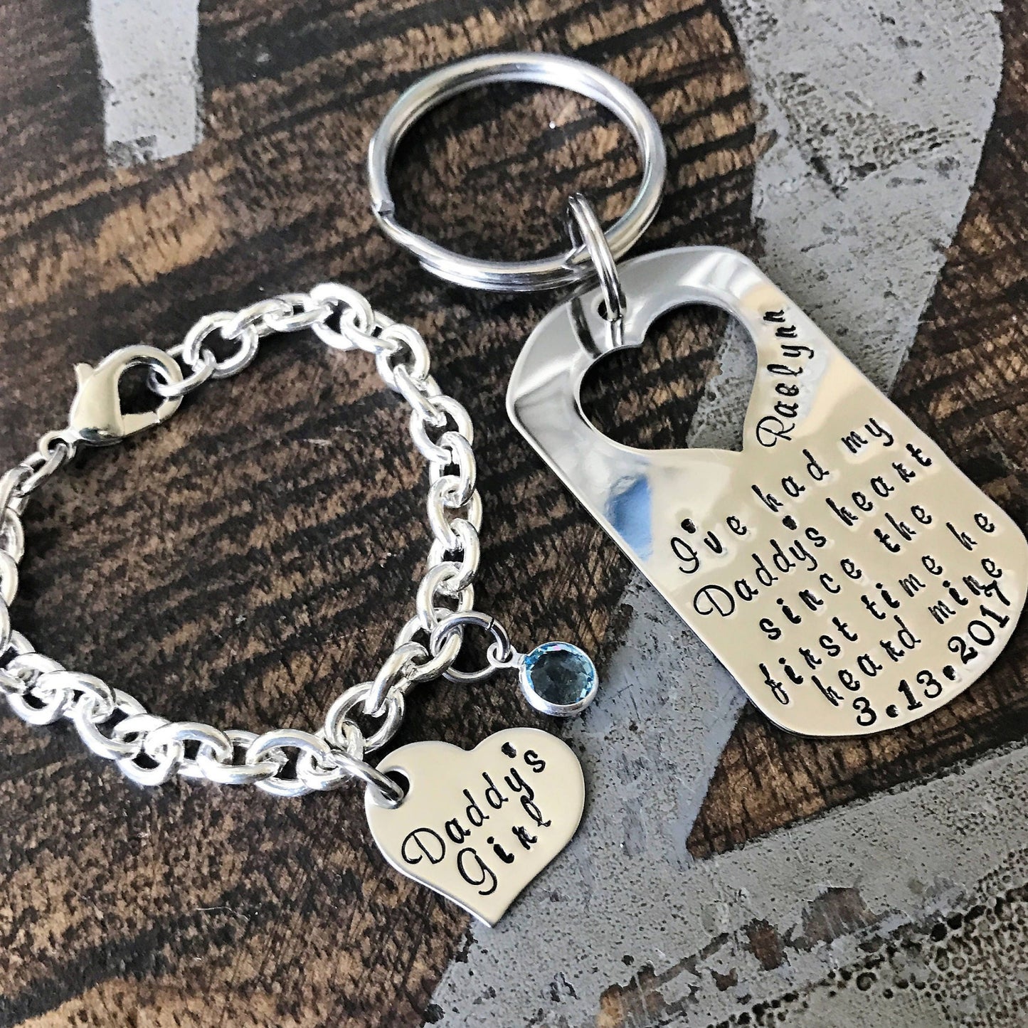 Silver keychain and bracelet set with engraved text on a wooden surface