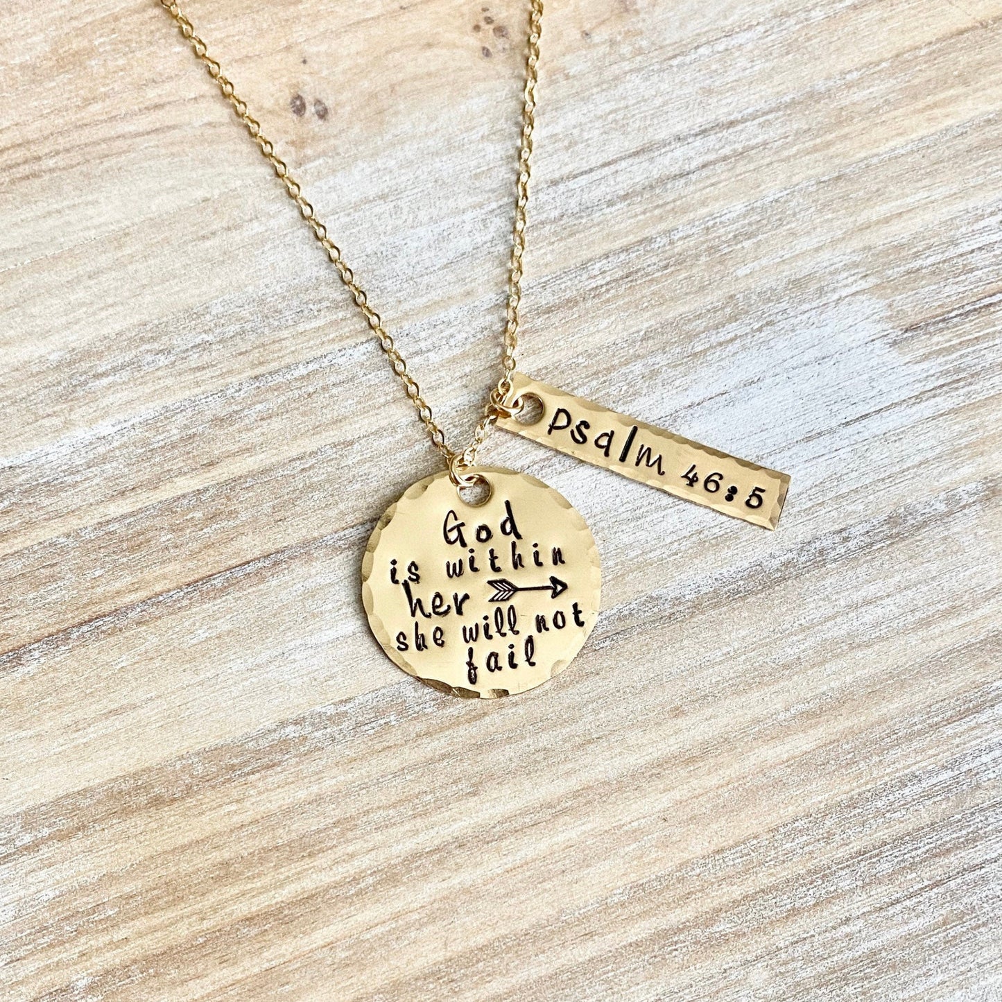 Gold necklace with two pendants on a wooden surface