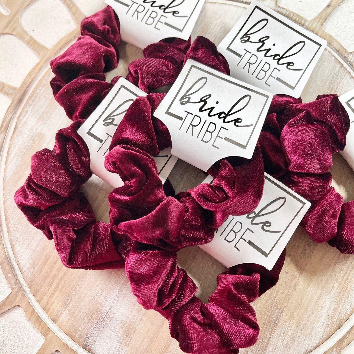 Burgundy scrunchies with 'Bride Tribe' cards on a decorative surface
