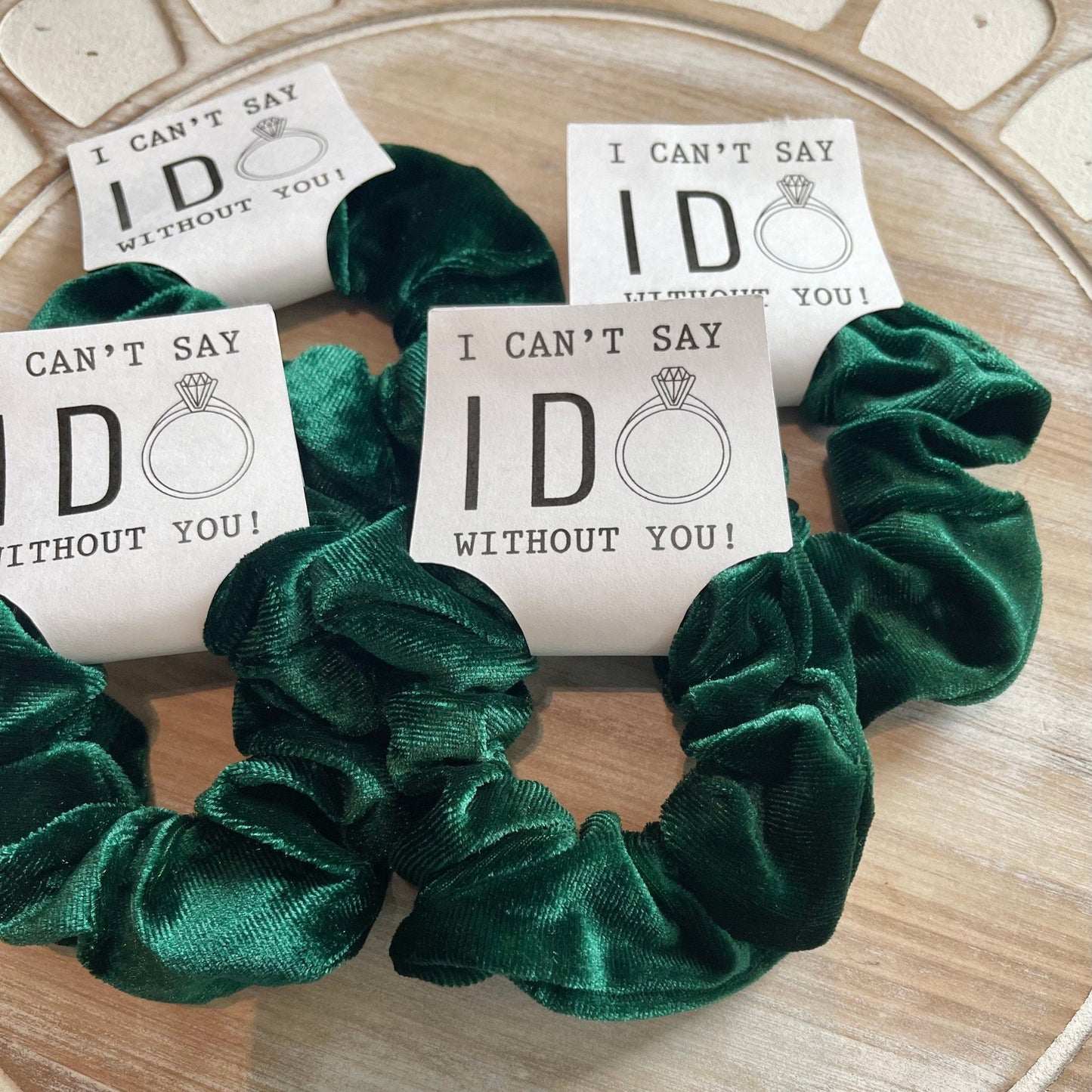 Green scrunchies with 'I can't say I do without you' cards on a wooden surface