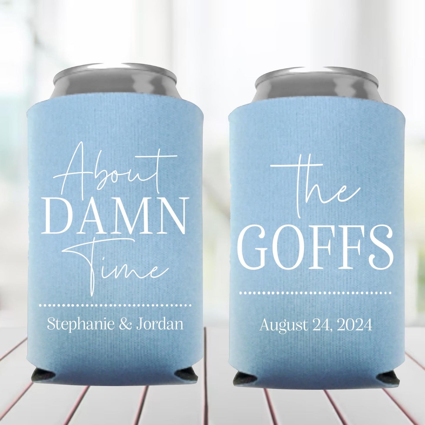 Two blue can coolers with personalized text on a wooden surface.