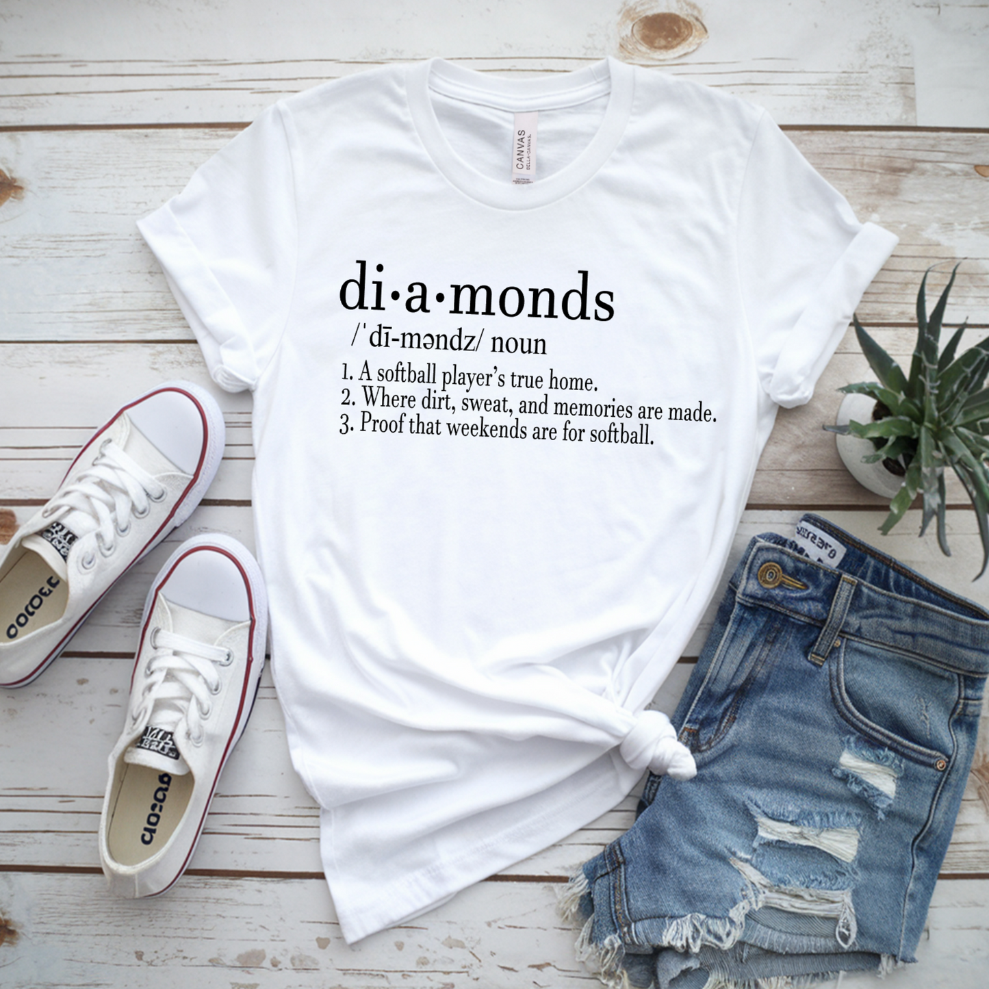White t-shirt with 'diamonds' definition text, Converse shoes, and denim shorts on a wooden surface.