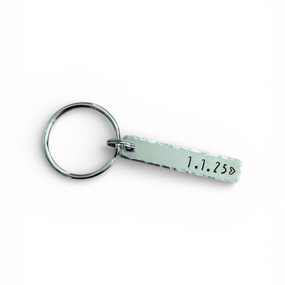 Keychain with a small rectangular tag featuring a date on a white background