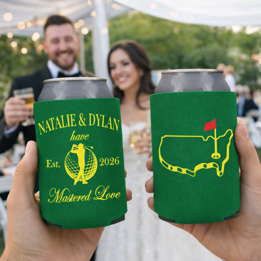 Two green can coolers with personalized designs held by a couple at an outdoor event.