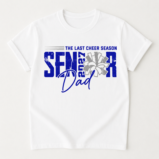 A white short-sleeve crewneck t-shirt with a blue and gray graphic on the front that reads 'THE LAST CHEER SEASON SENIOR 2027 Dad' with a stylized flower and star details.