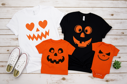 Halloween-themed t-shirts and a baby onesie with pumpkin designs on a wooden surface.