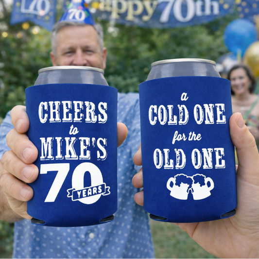 Two people holding blue can coolers with personalized text at a 70th birthday celebration.