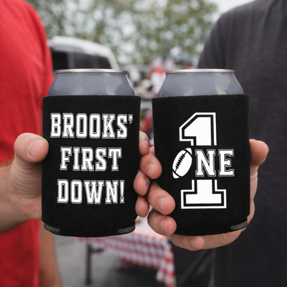 Two can coolers with personalized designs held by two people, one with 'Brooks' First Down!' and the other with '411'.