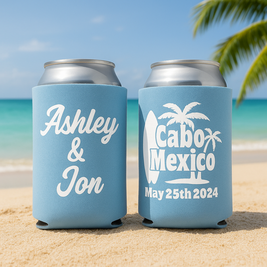 Two light blue can coolers with personalized text on a beach.