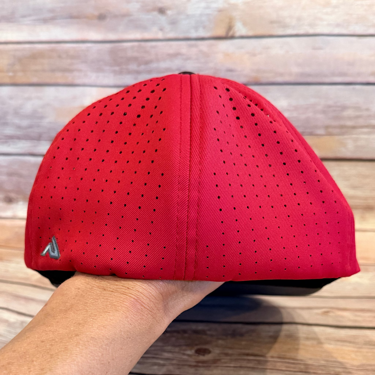 Red cap held by a hand on a wooden surface