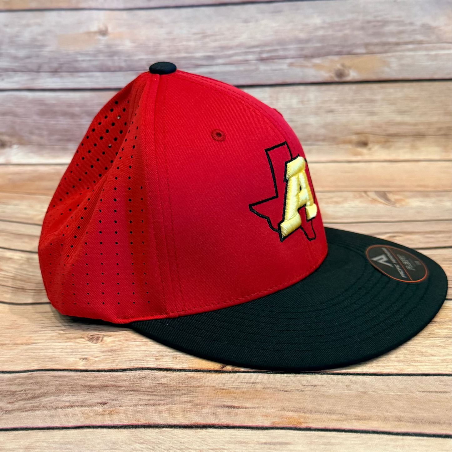 Red and black baseball cap with a logo on a wooden surface
