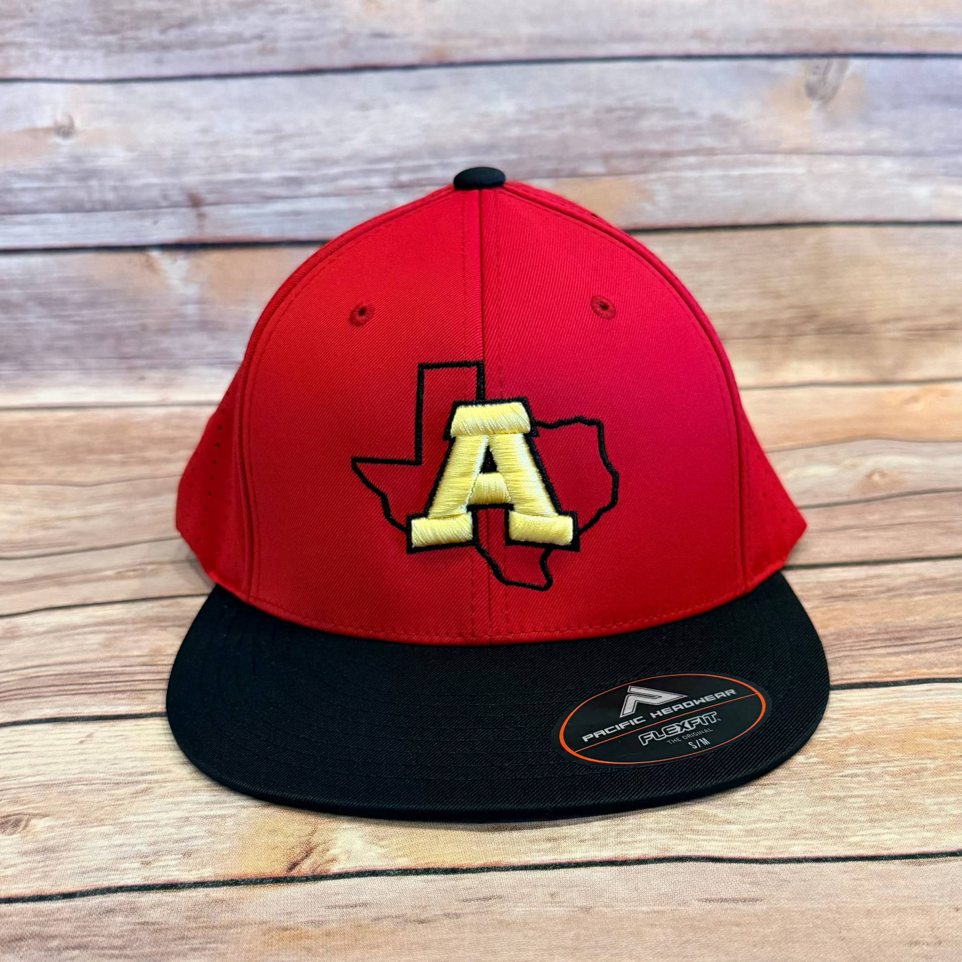Red and black cap with a yellow logo on a wooden surface