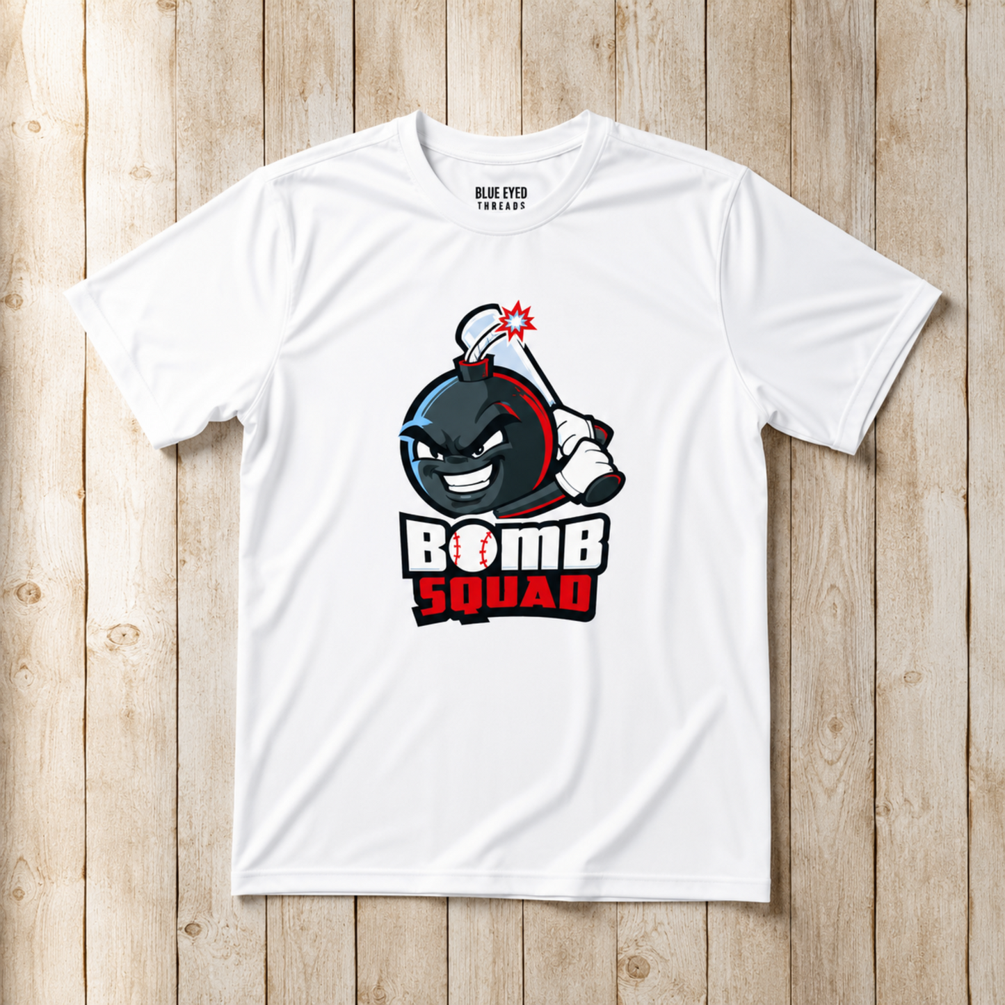 A white short-sleeve t-shirt with a cartoon bomb graphic and the text 'BOMB SQUAD' on the front, laid flat on a light wood plank background. The inside collar shows the brand name 'BLUE EYE TEE SHOP'.
