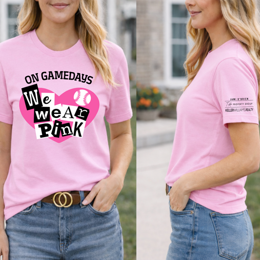 Woman wearing a pink t-shirt with a graphic design and text, standing outdoors.