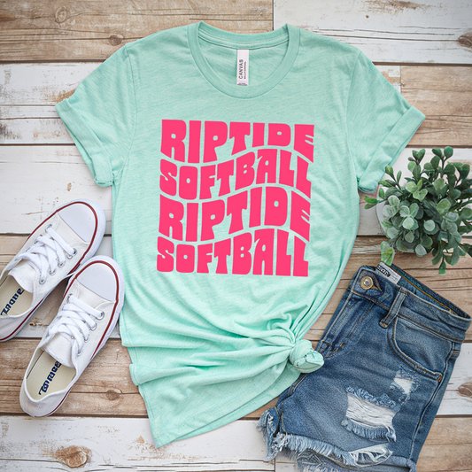 Mint green t-shirt with pink 'Riptide Softball' text, white sneakers, and denim shorts on a wooden surface.