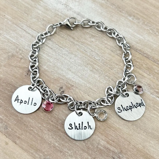Silver bracelet with engraved charms on a wooden surface