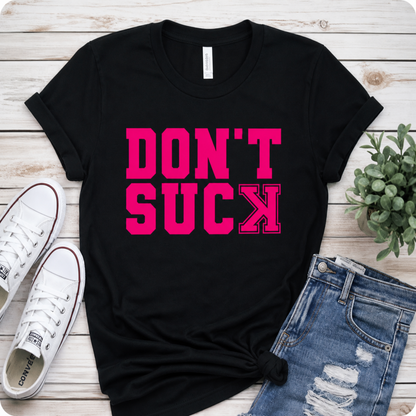 Black t-shirt with pink text 'DON'T SUCK', white sneakers, and blue jeans on a wooden surface.