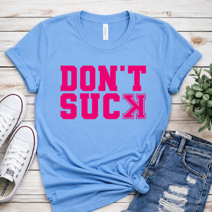 Blue t-shirt with 'DON'T SUCK' in pink on a wooden surface with shoes and jeans.