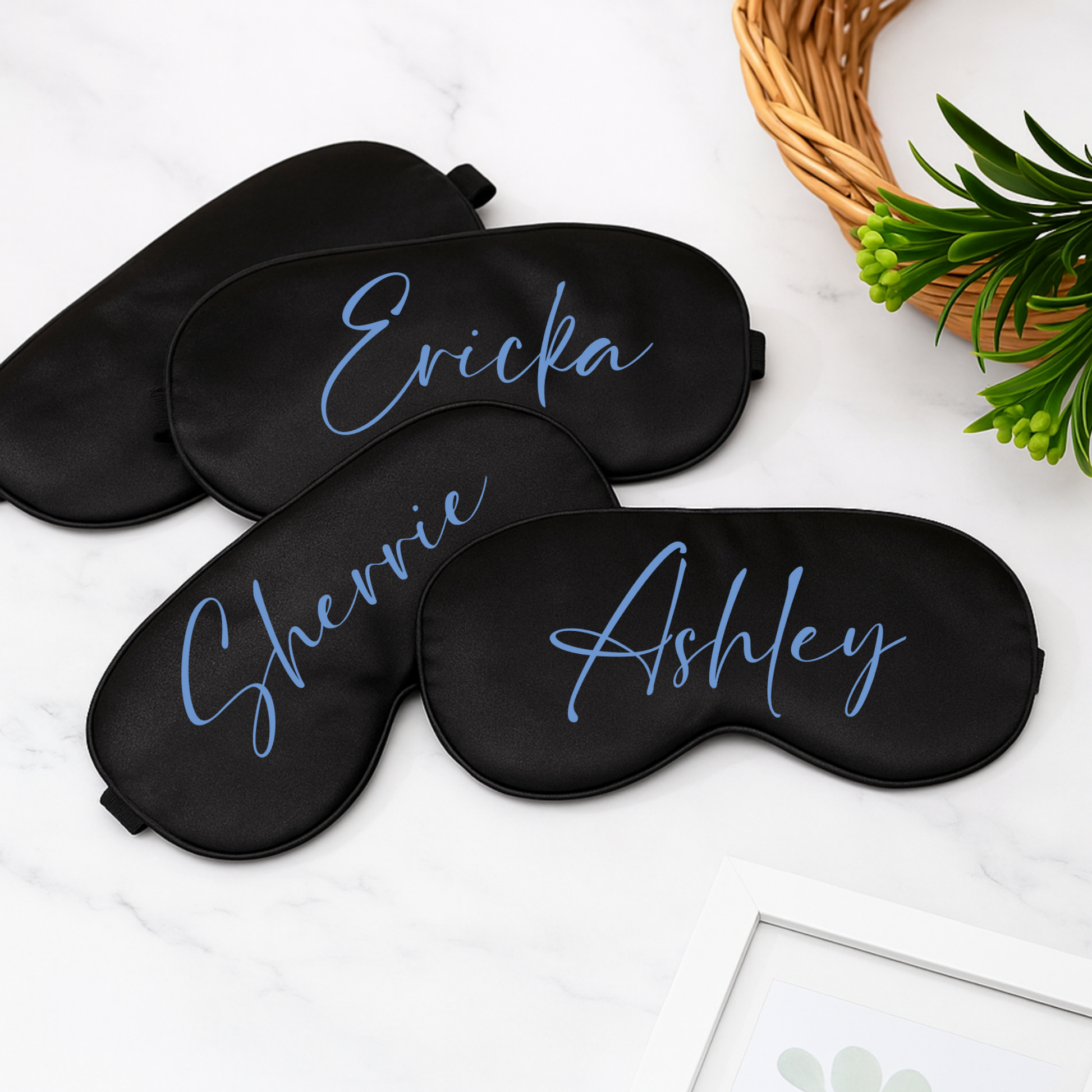 Three black sleep masks with personalized names on a white surface.