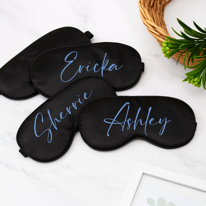 Three black sleep masks with personalized names on a white surface.