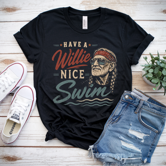 Black t-shirt with graphic design and text, paired with denim shorts and sneakers on a wooden surface.