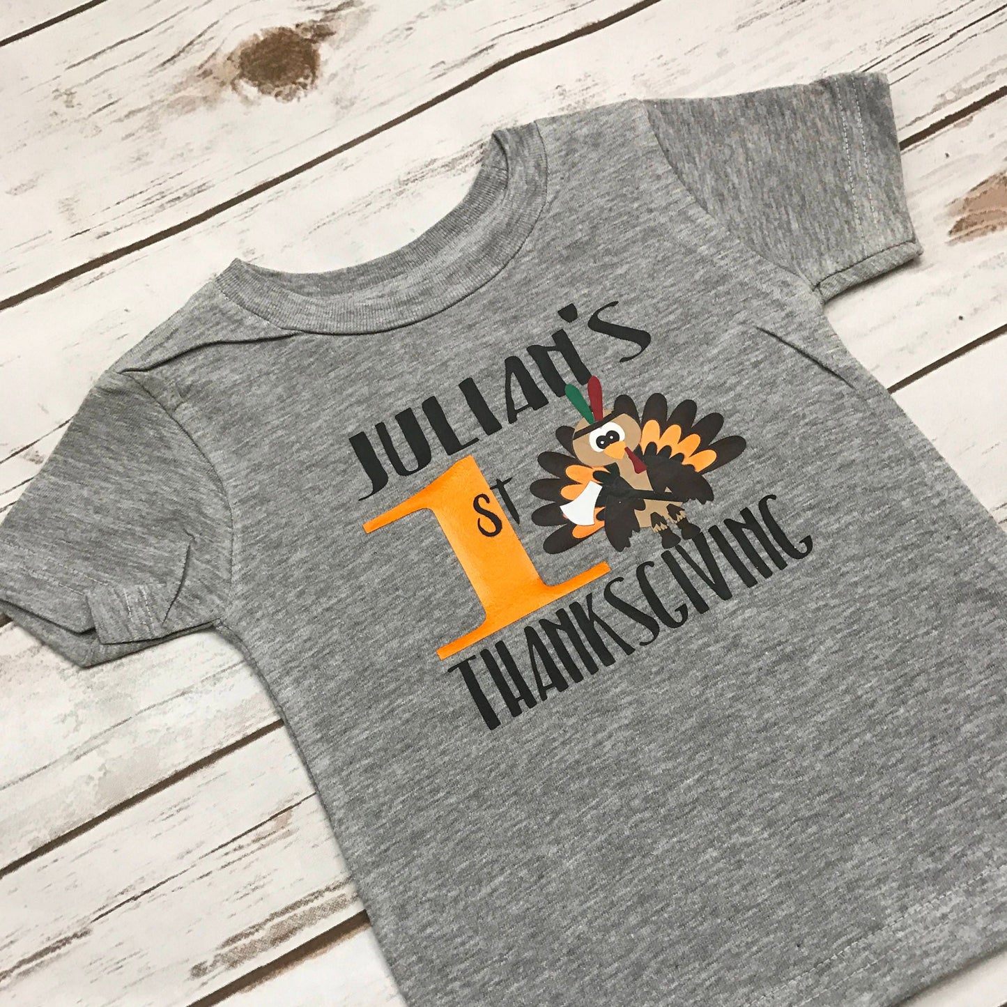 Gray t-shirt with a personalized Thanksgiving design on a wooden surface