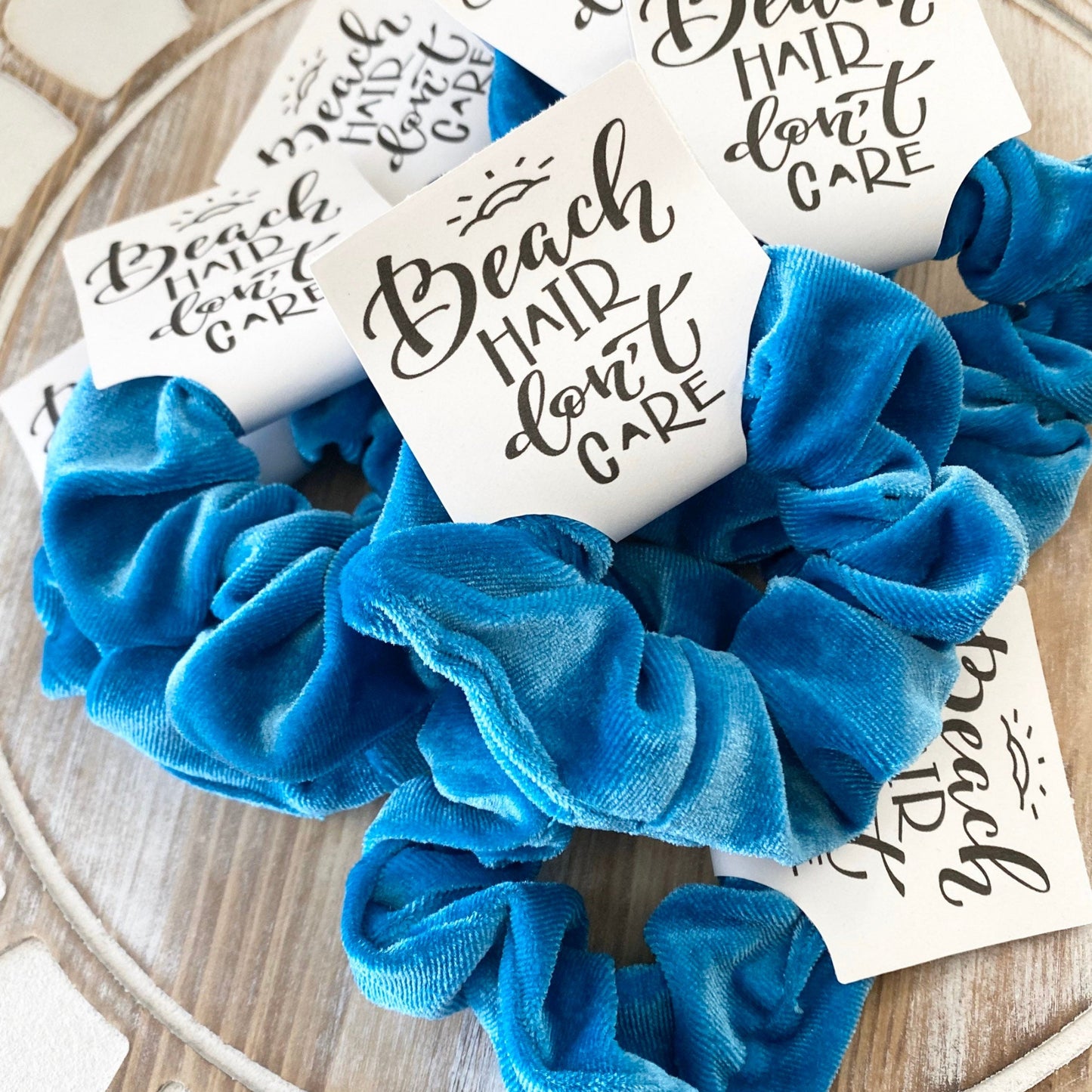 Blue scrunchie with 'Beach Hair Don't Care' cards on a wooden surface