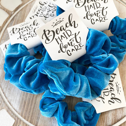 Blue scrunchie with 'Beach Hair Don't Care' cards on a wooden surface