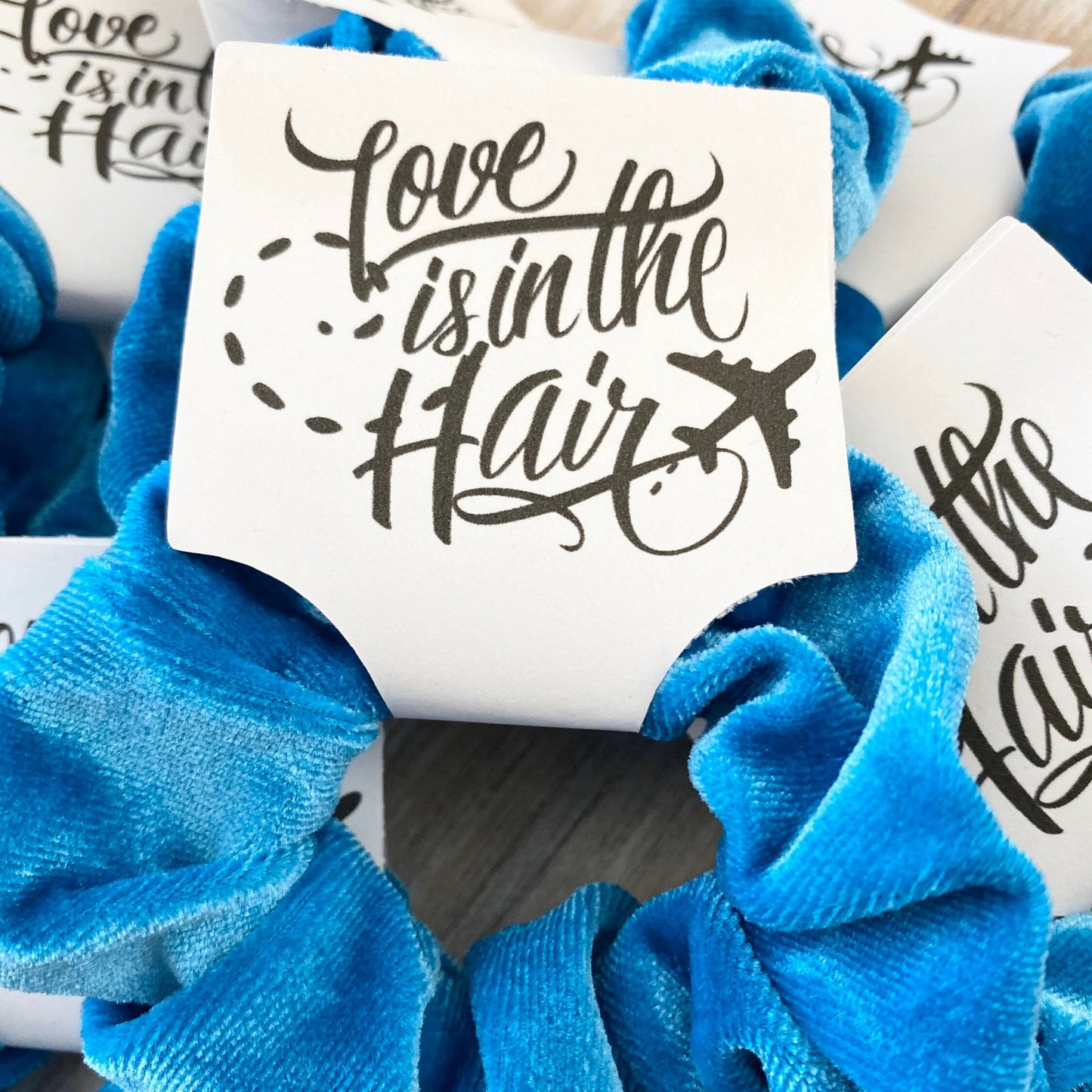 Blue scrunchies with 'Love is in the Hair' text on white cards.