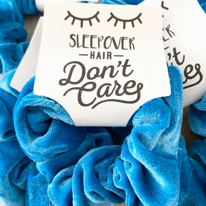 Blue scrunchies with 'Sleepover Hair Don't Care' text on a wooden surface