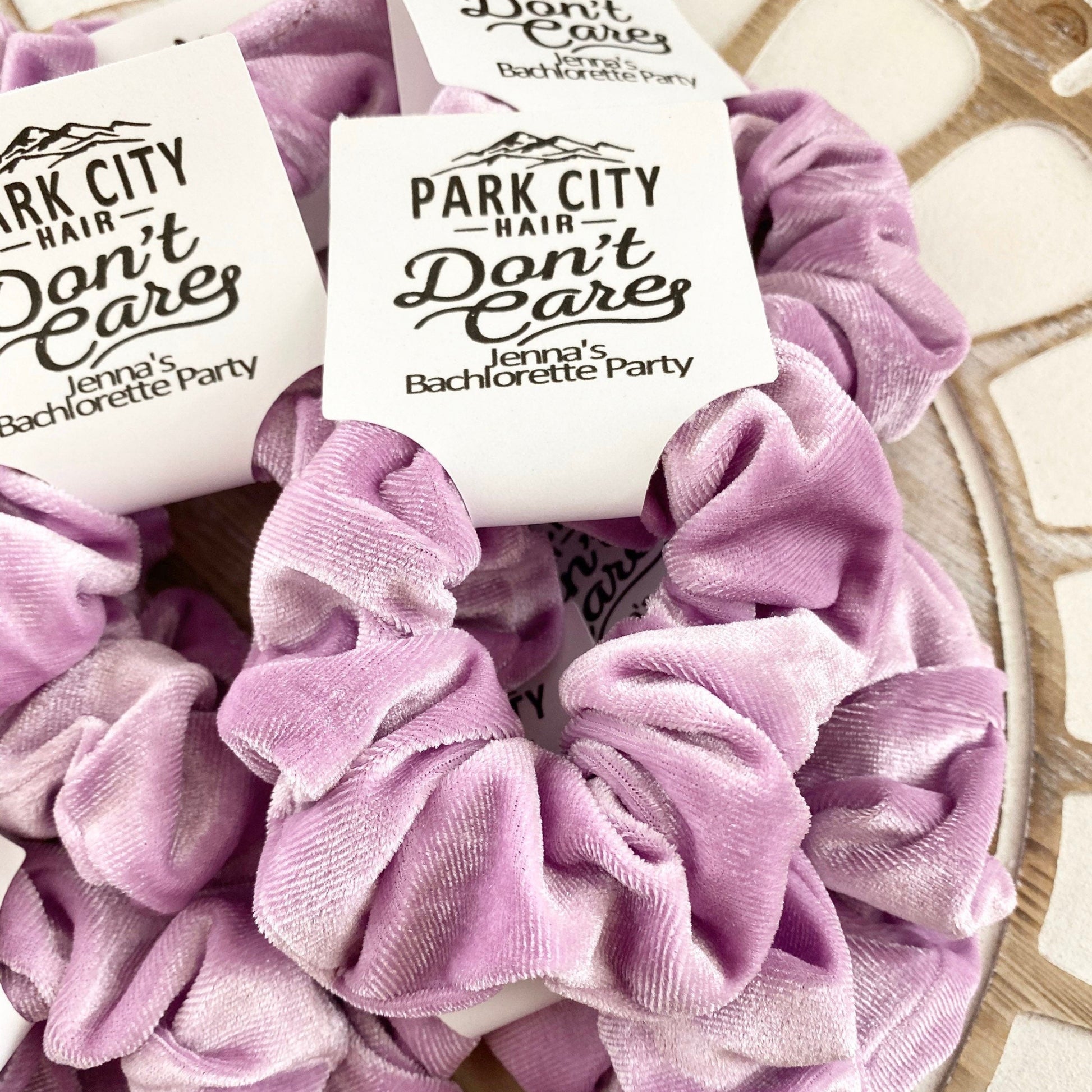 Purple scrunchies with 'Park City Hair Don't Care' labels on a textured surface.