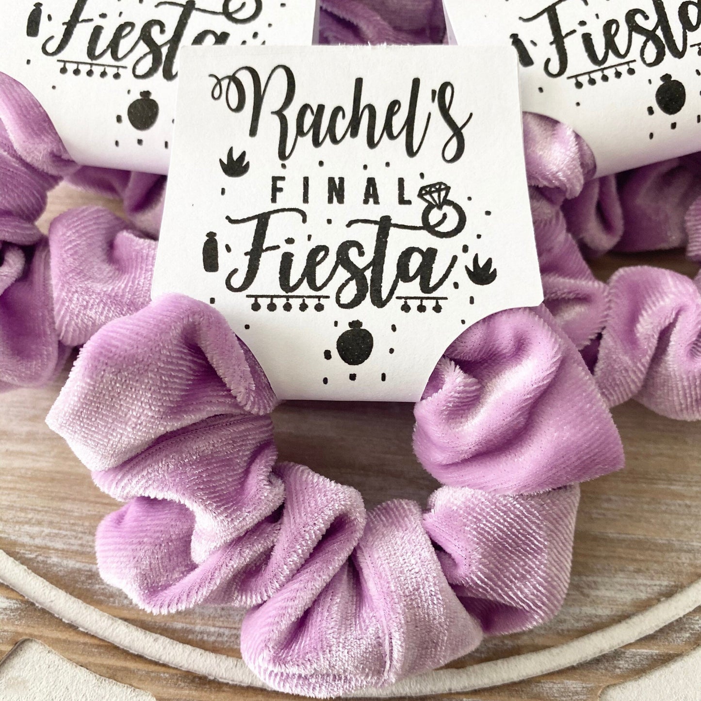 Purple scrunchie with 'Rachel's Final Fiesta' card on a wooden surface