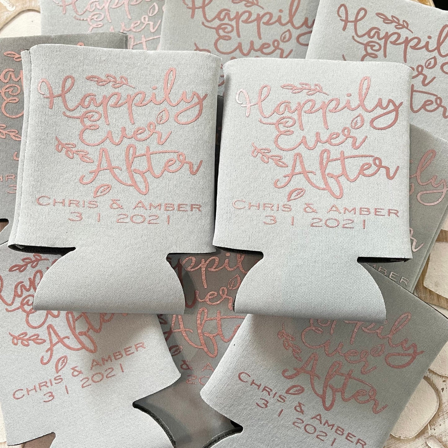 Koozies with 'Happily Ever After' text and personalized names and date on a neutral background.