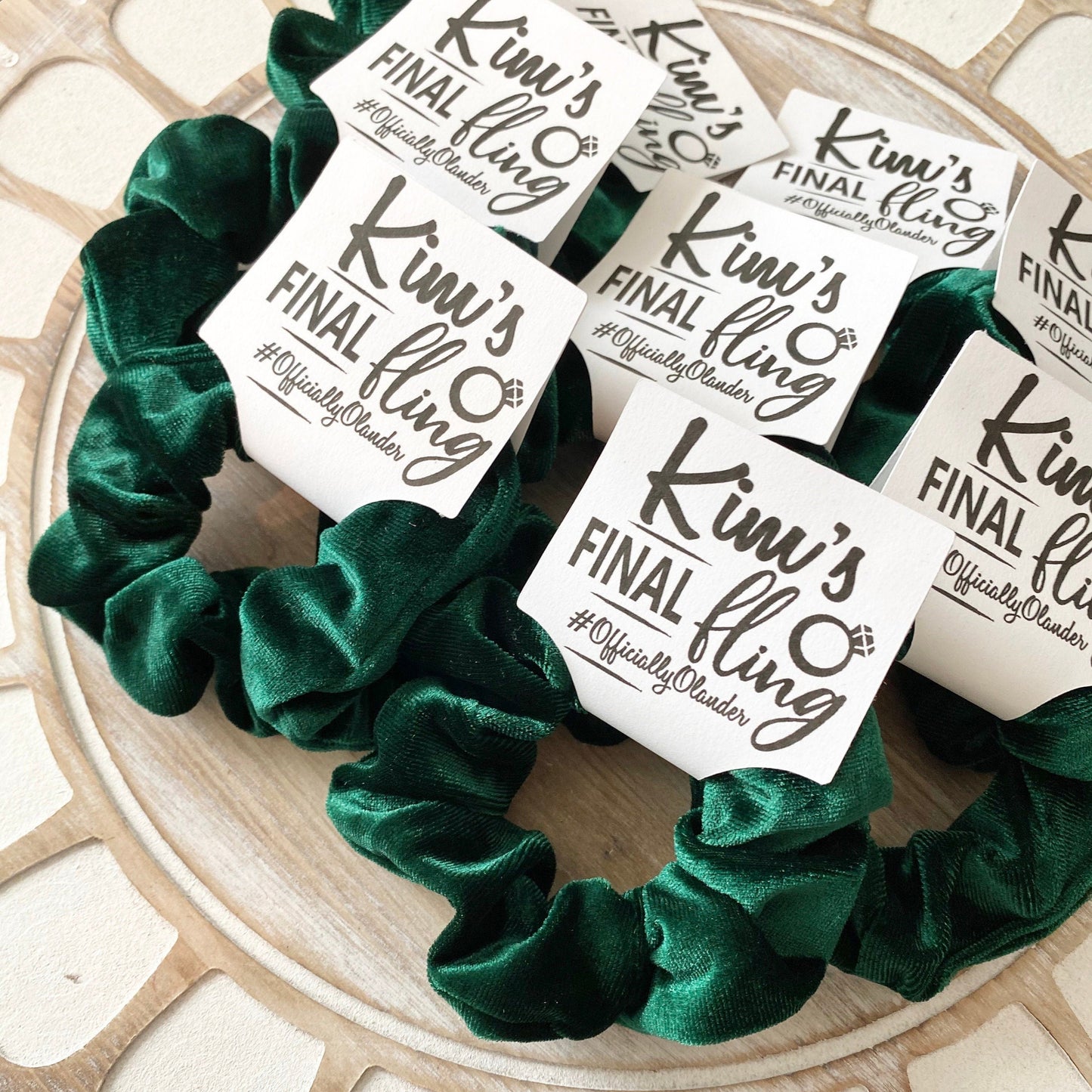 Green scrunchie with 'Kim's Final Fling' labels on a decorative surface