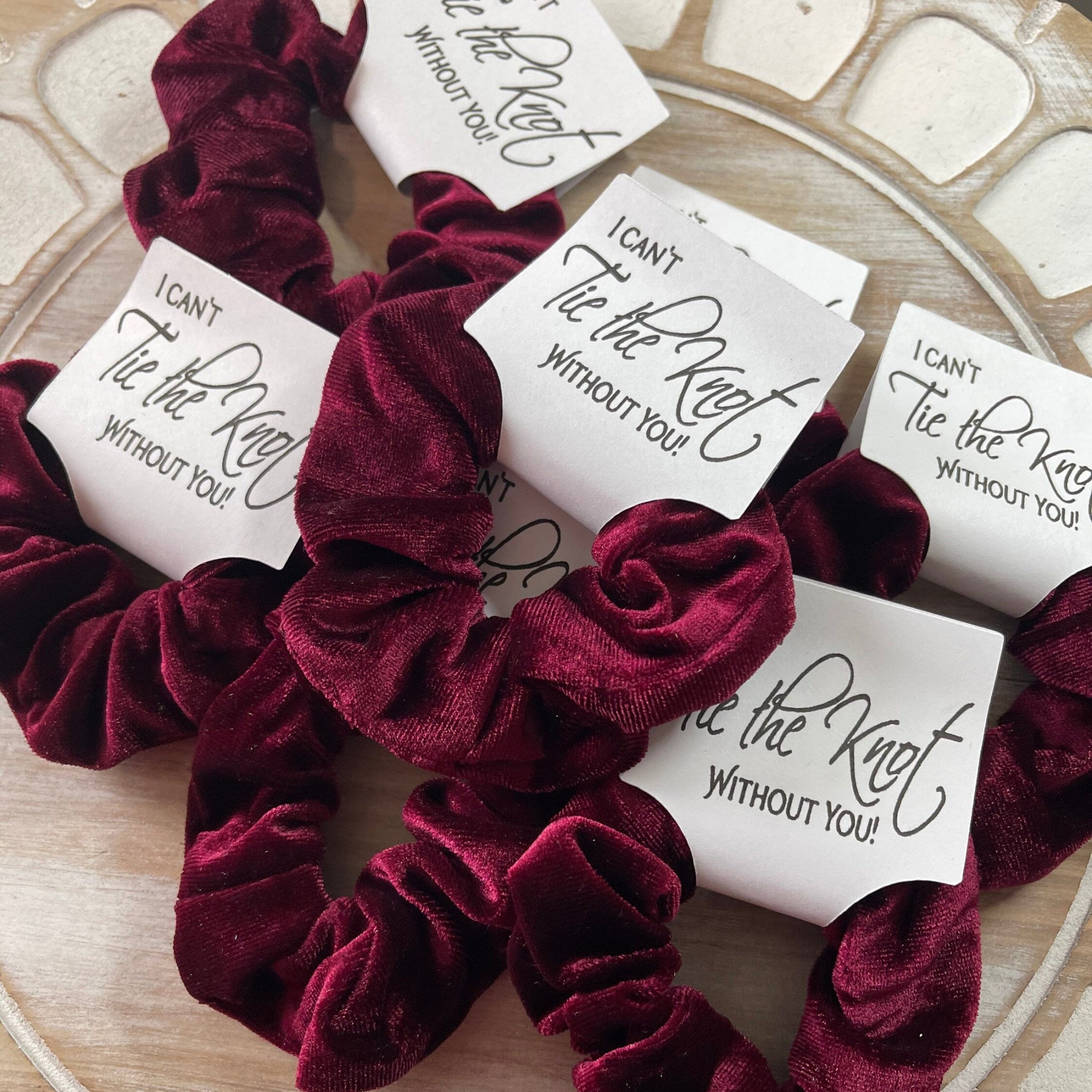 Burgundy scrunchies with 'I can't tie the knot without you' notes on a decorative plate.