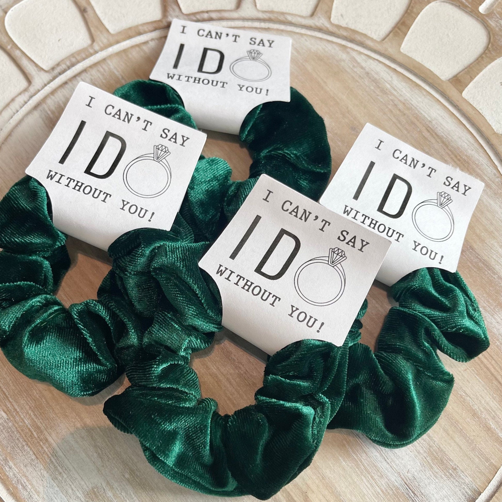 Green scrunchies with 'I can't say I do without you' cards on a wooden surface