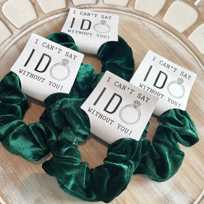 Green scrunchies with 'I can't say I do without you' cards on a wooden surface