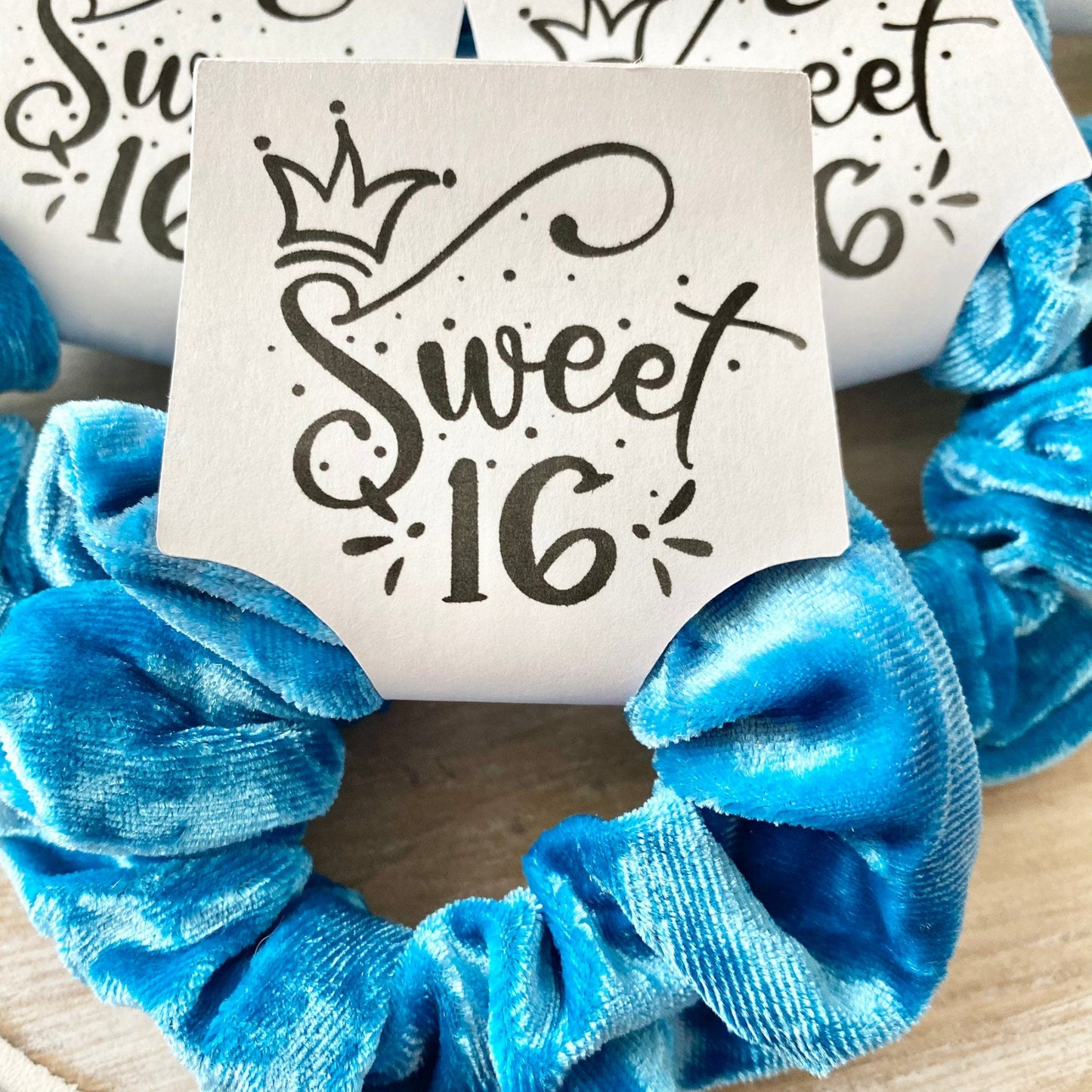 Blue scrunchies with 'sweet 16' sign on a wooden surface