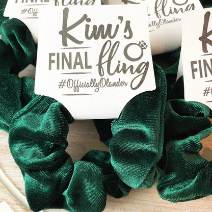 Green scrunchies with a 'Kim's Final Fling' label on a wooden surface