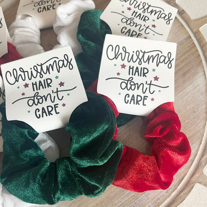 Green and red scrunchies with 'Christmas Hair Don't Care' labels on a wooden surface.