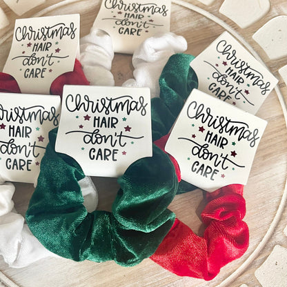 Green and red scrunchies with 'Christmas Hair Don't Care' cards on a wooden surface.