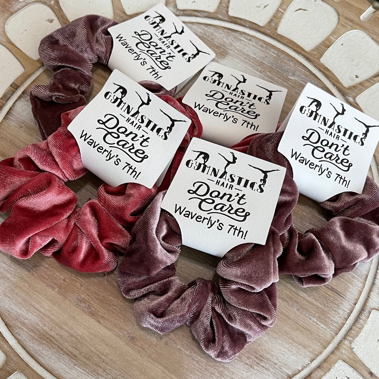 Set of scrunchies with personalized labels on a wooden surface