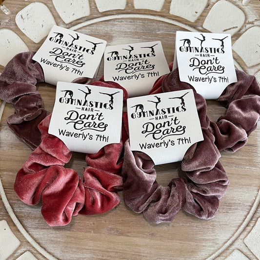 Velvet scrunchies with personalized labels on a wood surface