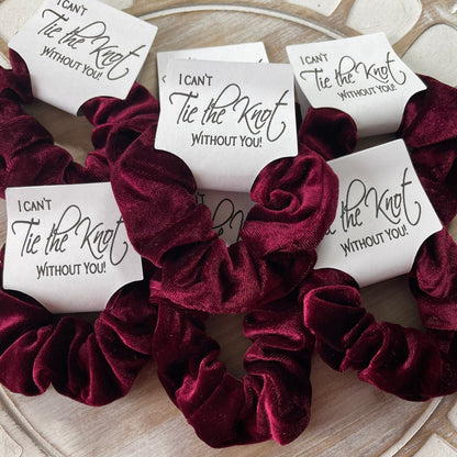 Maroon velvet scrunchies with 'I can't tie the knot without you' cards on a wooden surface.