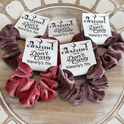 Velvet scrunchies with personalized labels on a decorative surface