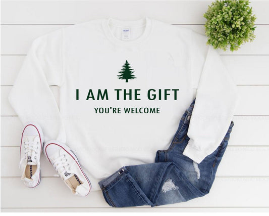 White sweatshirt with 'I AM THE GIFT YOU'RE WELCOME' text, jeans, and sneakers on a white wooden surface.