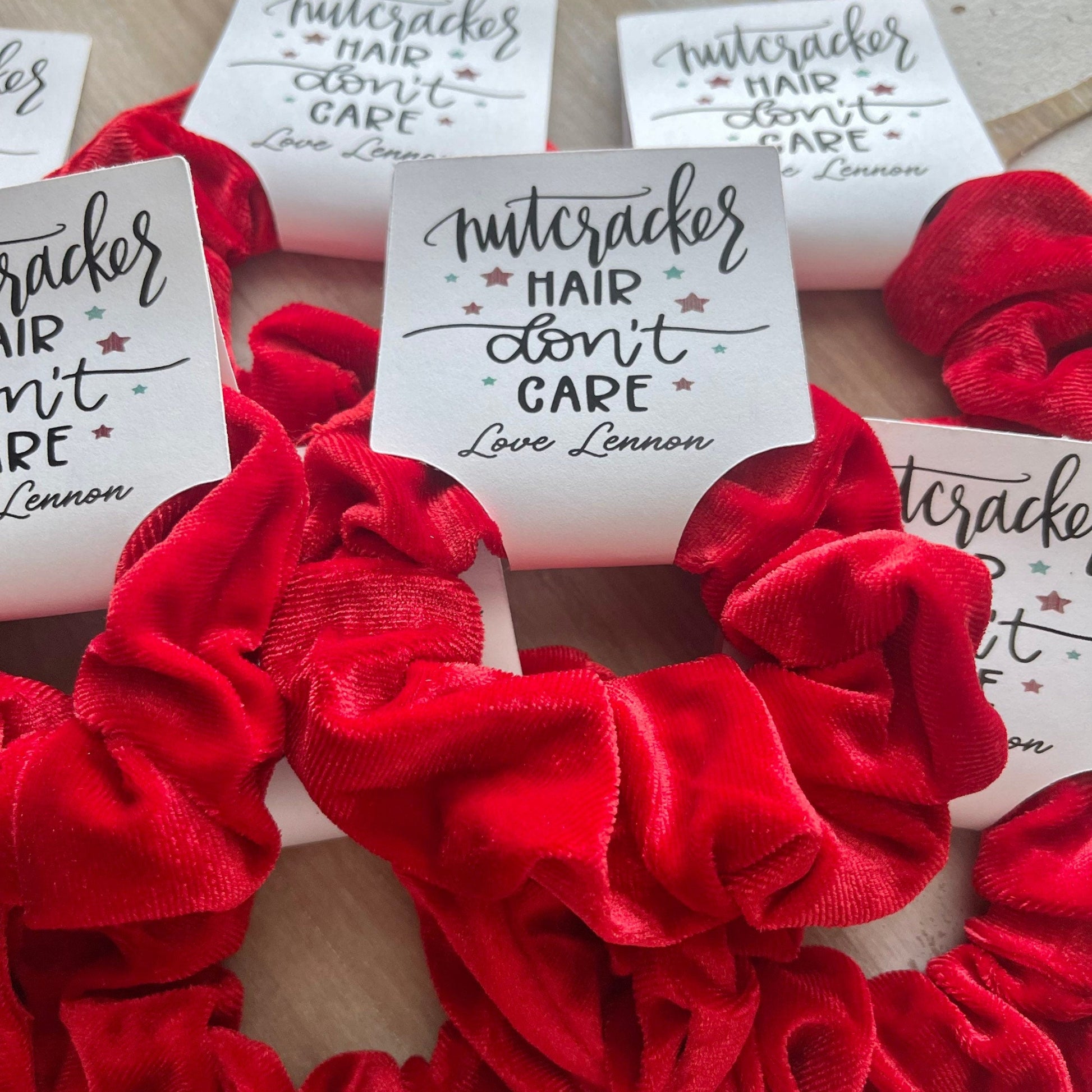 Red scrunchies with personalized labels on a wooden surface