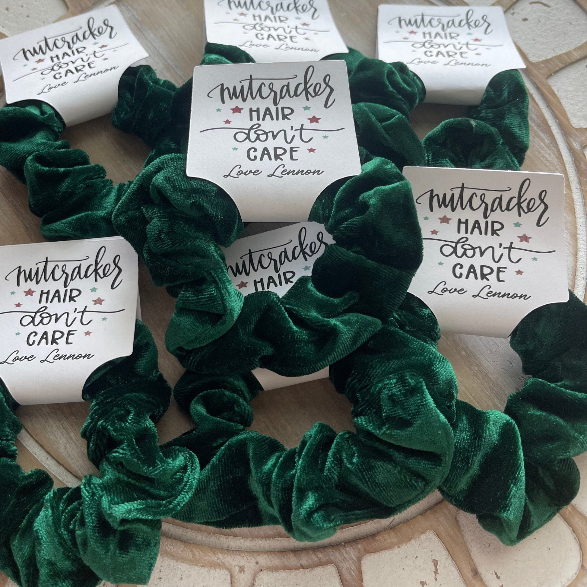 Green scrunchies with 'Nutcracker Hair Don't Care' labels on a textured surface