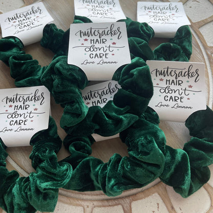 Green scrunchies with 'Nutcracker Hair Don't Care' labels on a textured surface