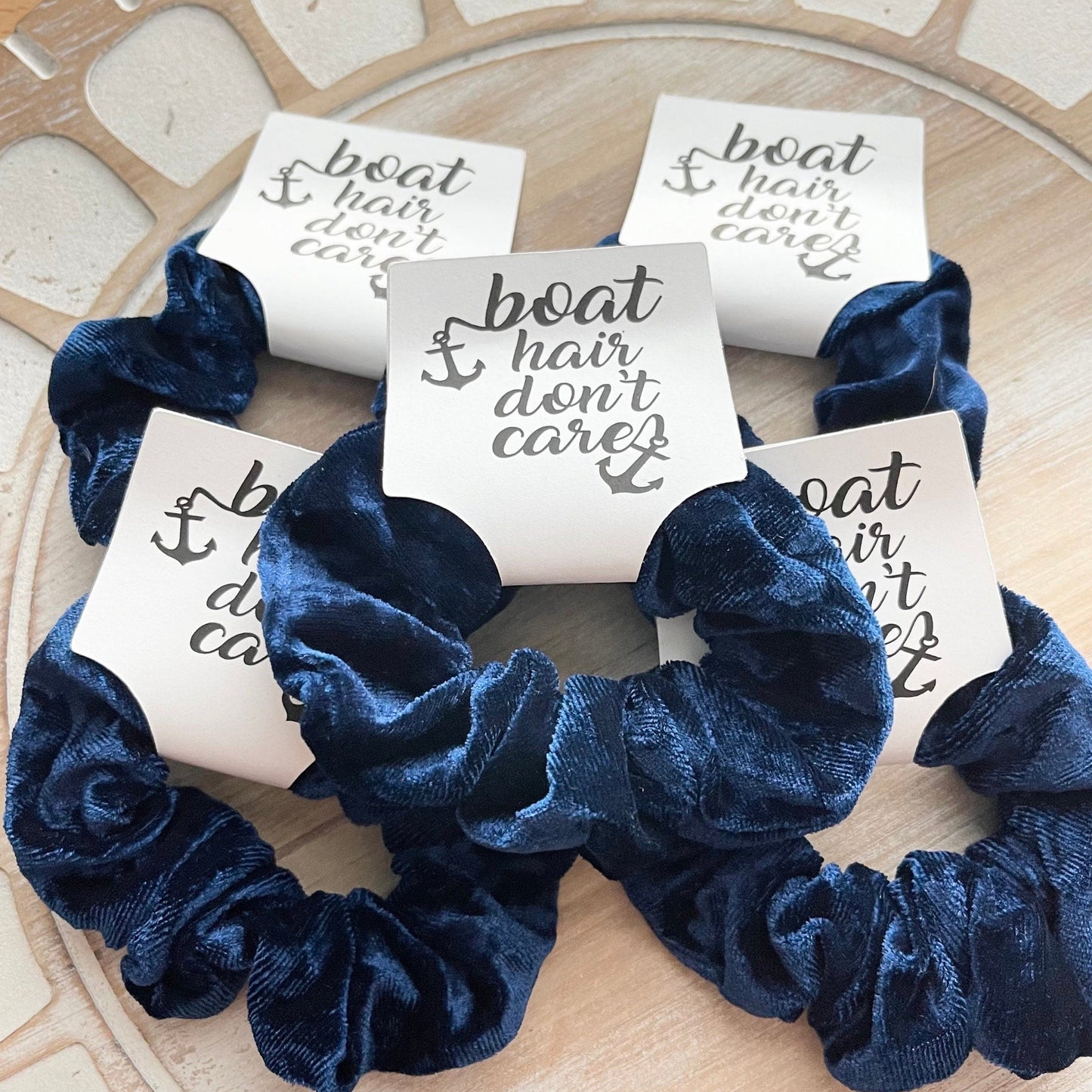 Navy blue scrunchies with 'boat hair don't care' cards on a decorative surface